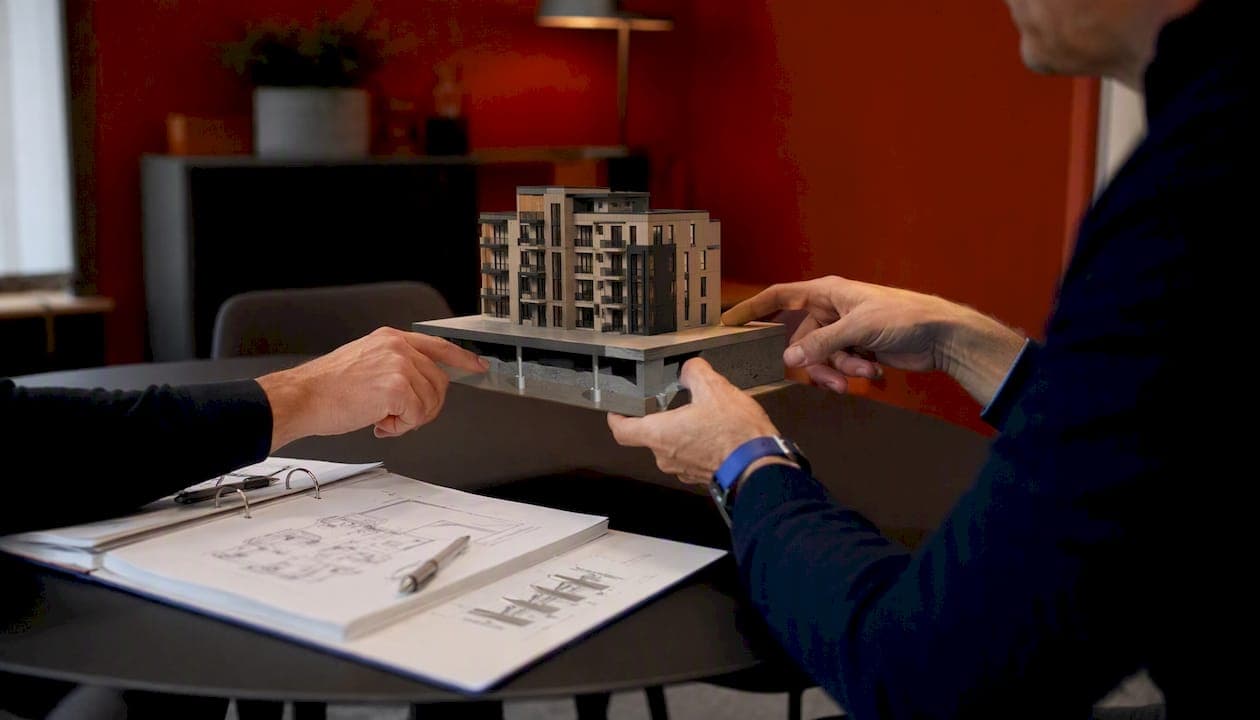 Handen geven uitleg bij de maquette van het funderingstype van de woning