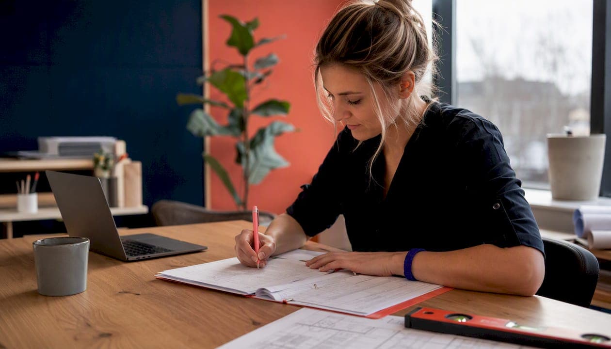 Detailopname van handen die een bouwkundig rapport opstellen