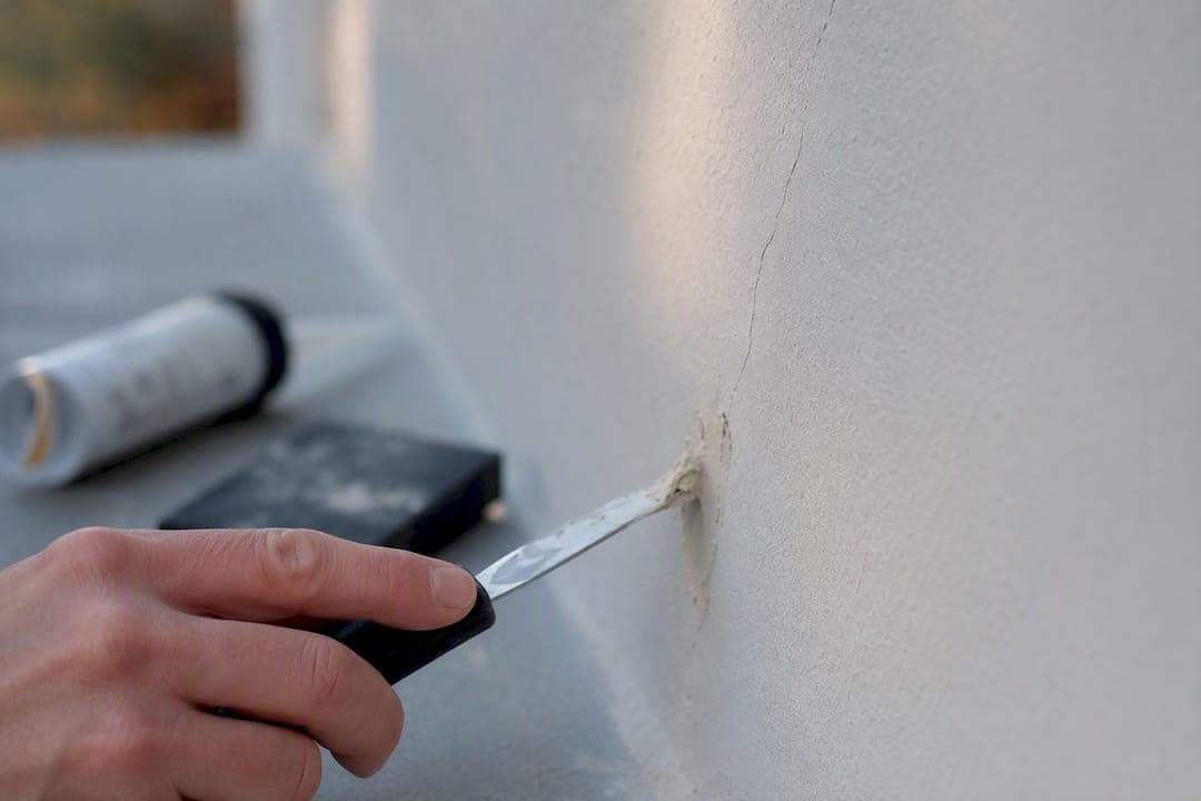 Met de hand een scheur in de muur opvullen met plamuur